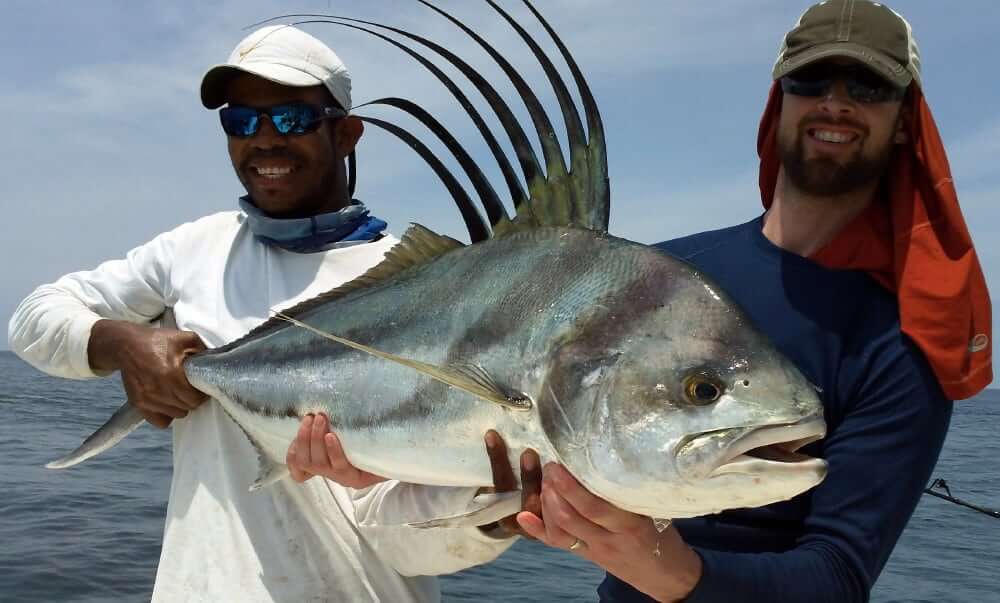 Mate and angler holding a panama roosterfish aboard the T.O.P. CAT