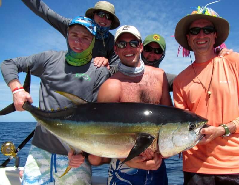 Celebrating anglers posing for picture holding medium sized yellowfin tuna