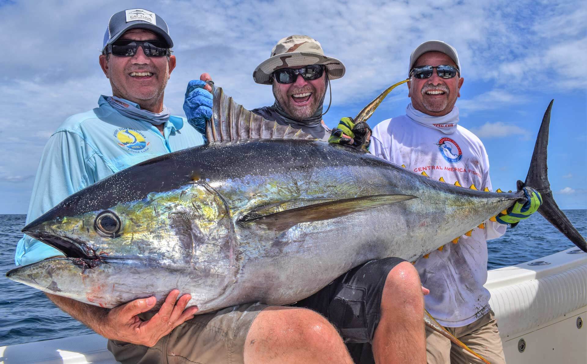 3 smiling anglers posing with tuna