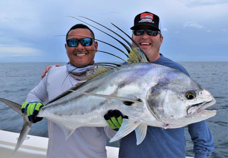 Mate Juan posing with roosterfish and smiling angler. Sport Fish Panama Island Lodge