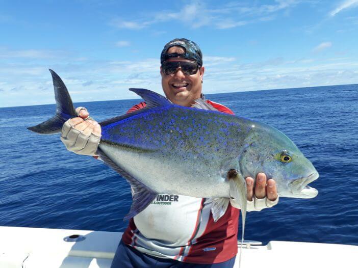 Angler holding Bluefin Trevally while having picture taken