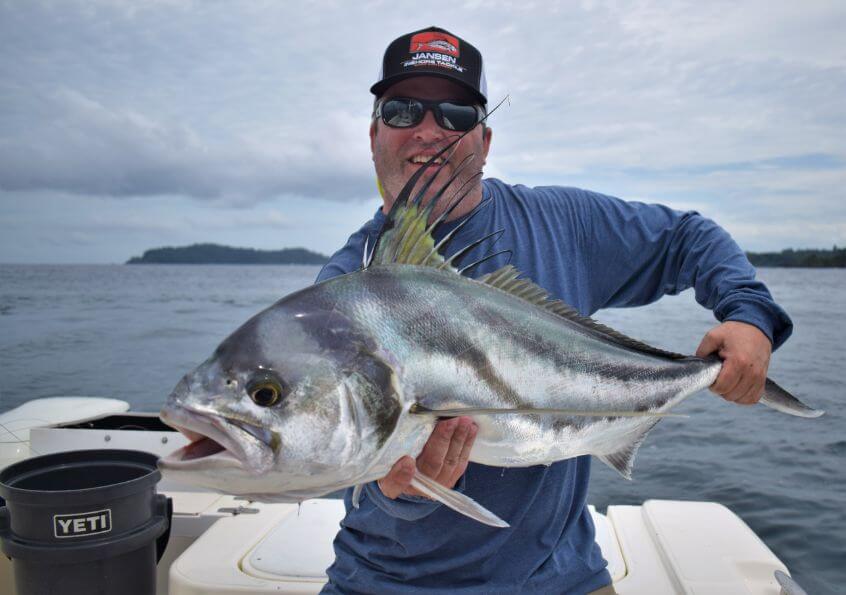 Angler holding roosterfish with Isla Parida, Panama in the background.