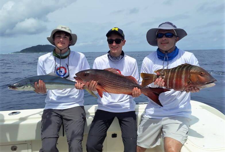 3 anglers posing with their catch at Isla Montuosa, Panama in background.