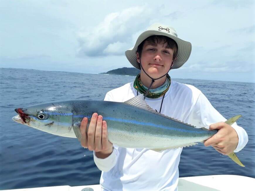angler posing with  Sierra Mackerel or Spanish Mackerel   Isla Montuosa, Panama in background.