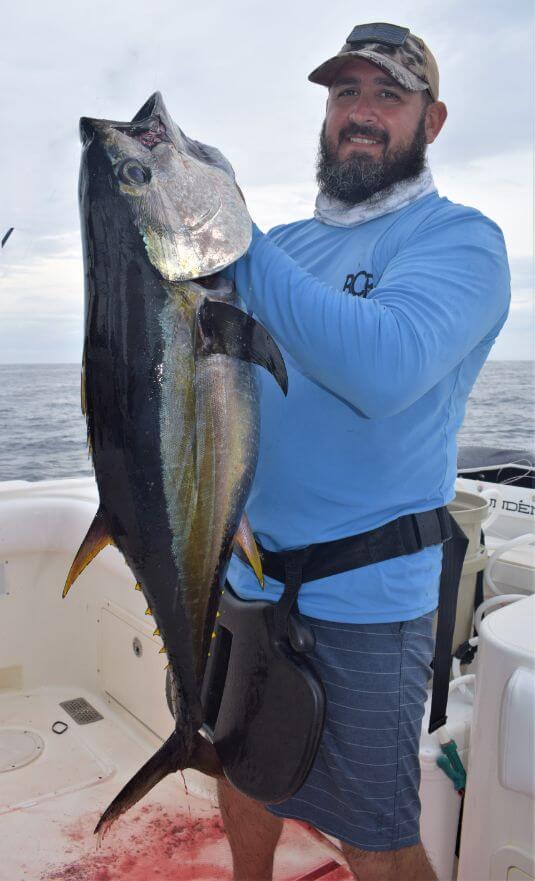Bearded angler holding yellowfin tuna while posing for picture