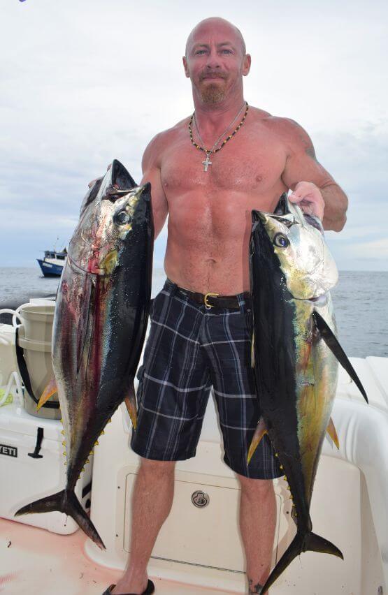 Angler holding two yellowfin tuna posing for picture