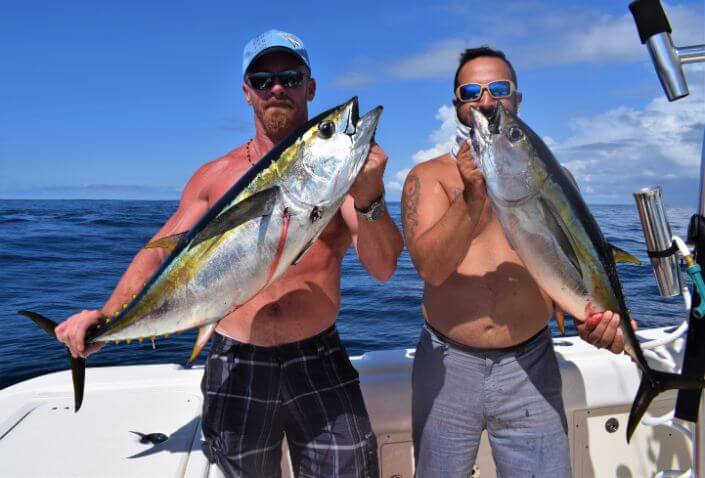 Two anglers posing with two small yellowfin tuna