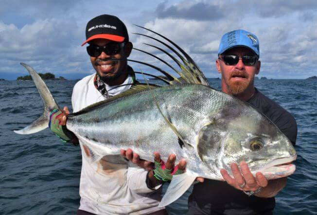 Mate and angler posing with nice roosterfish. Panama islands in background