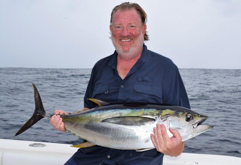 Bearded angler holding small yellowfin tuna