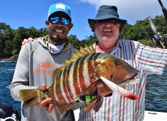 Mate with anglers hand on his shoulder holding Mexican Barred Snapper with lure still in mouth.