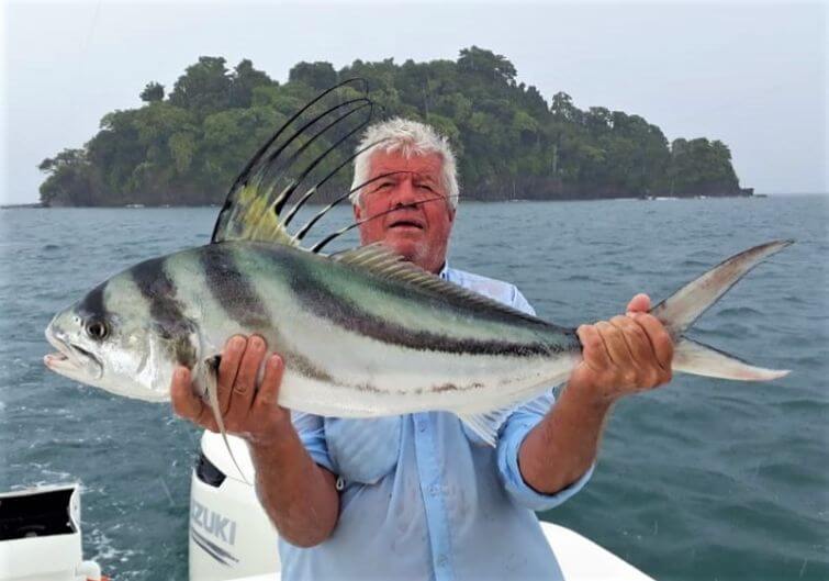 angler posing with roosterfish. Small Panama island in the background