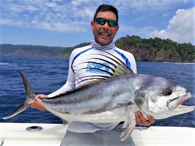 Angler posing with roosterfish and Isla Parida in background