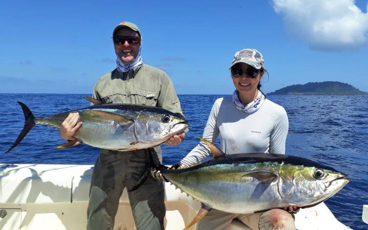 Smiling couple posing with just caught yellowfin tuna. Isla Montuosa in background.