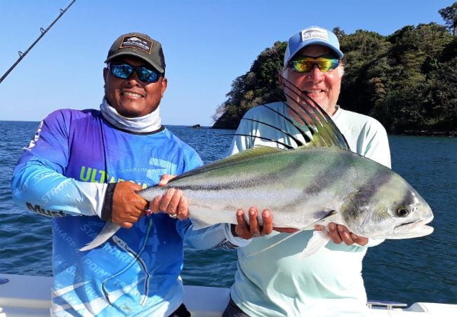 Mate holding Roosterfish for smiling angler at Sport Fish Panama Island Lodge