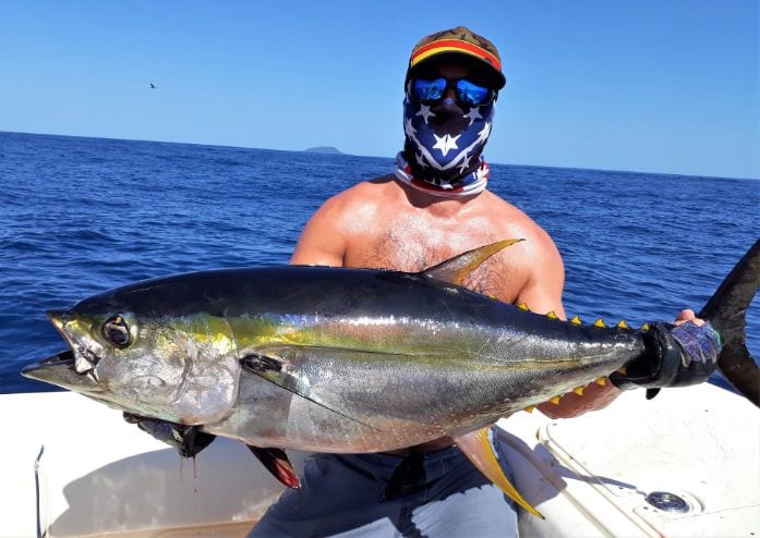 Angler holding 30 pound yellowfin tuna with Isla Montuosa in background