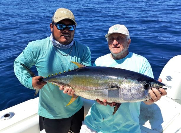 Mate and client holding small yellowfin tuna