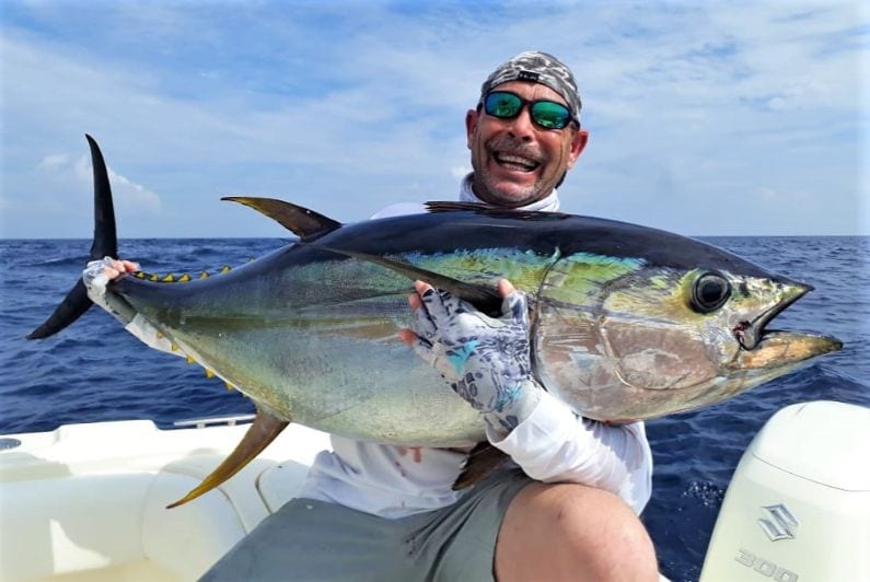Angler with big smile holding yellowfin tuna for photo op