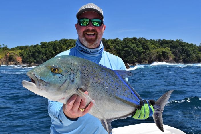 angler posing with Bluefin Trevally. Isla Parida in background