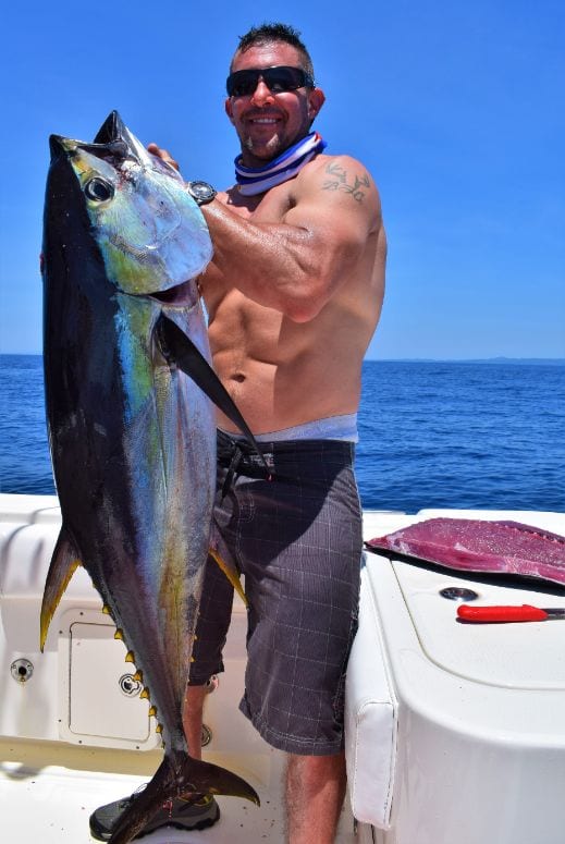 Angler with a tattoo posing with yellowfin tuna 
