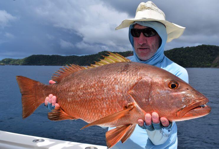  Angler posing with large cubera snapper. Isla Parida, Panama in the background.