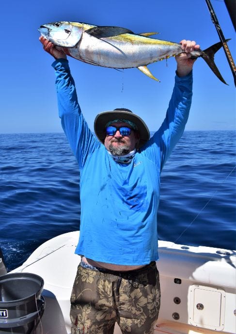 Angler holding small yellowfin tuna over his head of picture