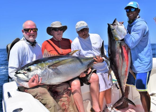 3 Smiling anglers holding two medium sized Yellowfin tunas