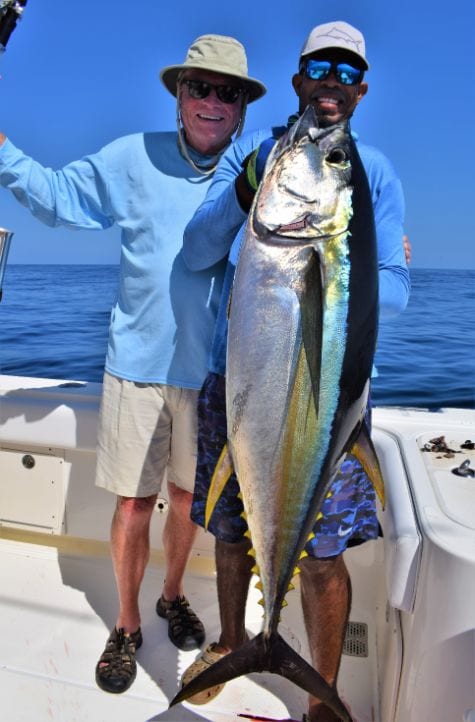Smiling angler and mate holding 100 pound Yellowfin tuna