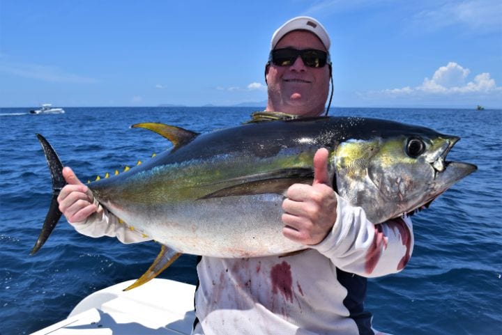 Angler posing for picture holding Yellowfin Tuna with two thumbs up