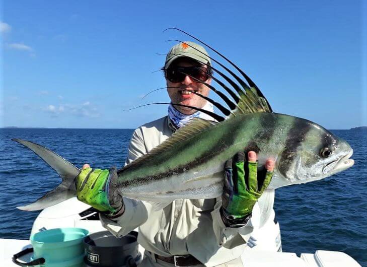 Angler with green gloves posing with roosterfish