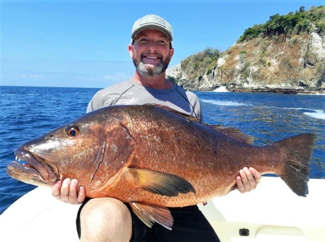 client holding cubera snapper with Isla Ladrones in the background