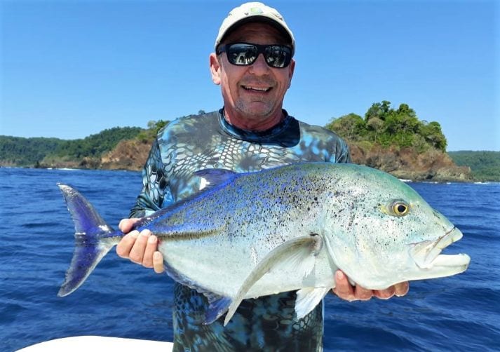 angler holding Bluefin Trevally with Isla Parida in background