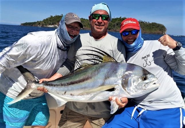 3 anglers posing with small roosterfish and small island in background