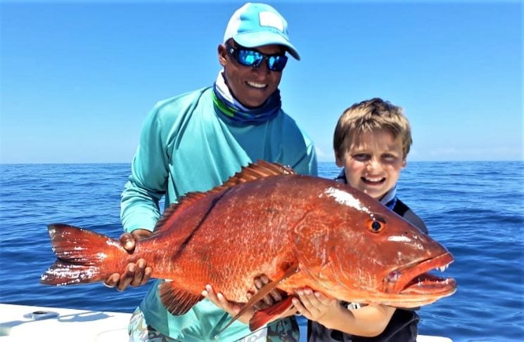 Mate holding cubera snapper for young angler