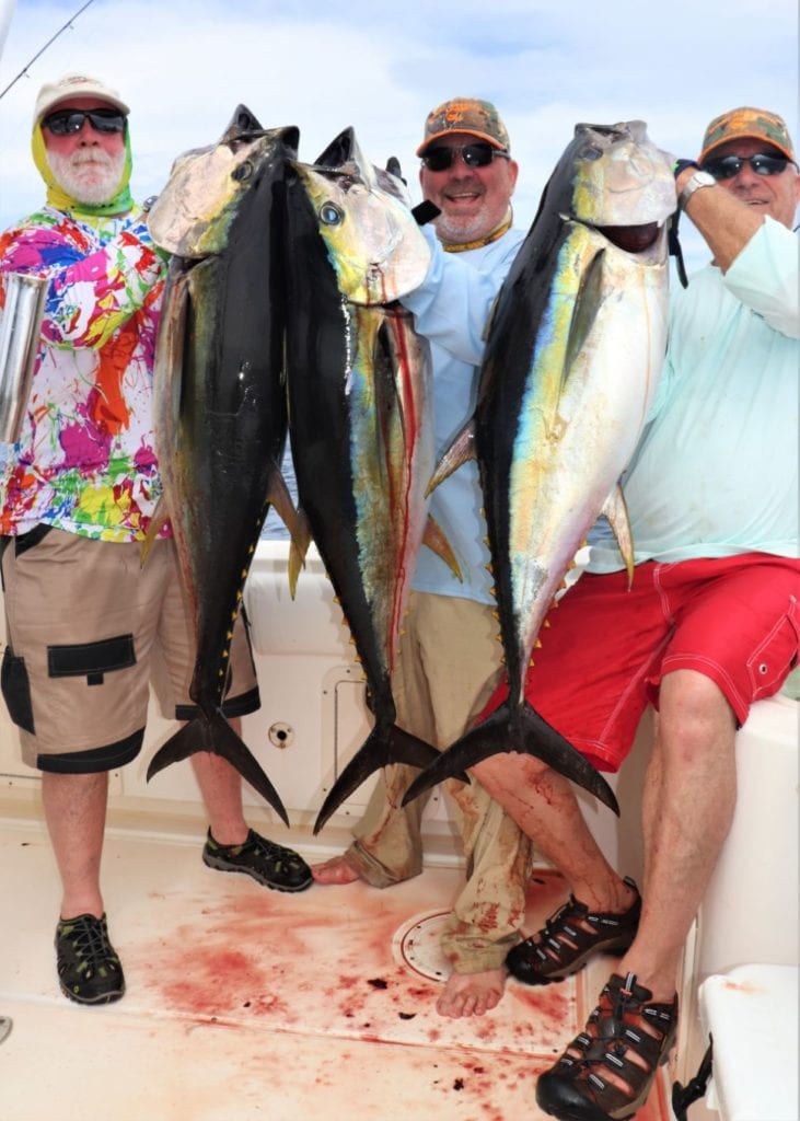 3 smiling anglers posing with tuna