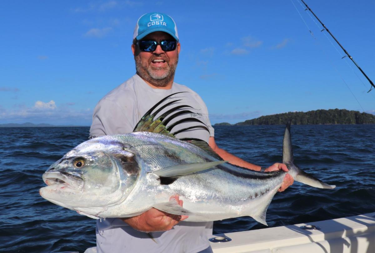Bearded angler holding roosterfish with Isla Parida in background