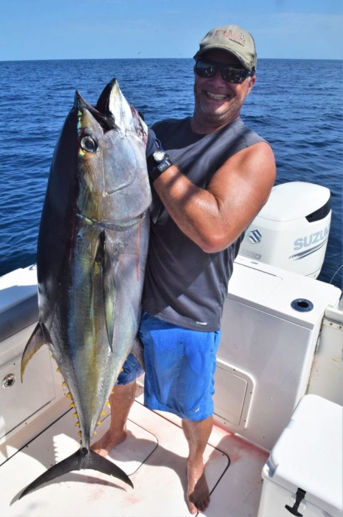 Smiling angler holding yellowfin tuna for picture.