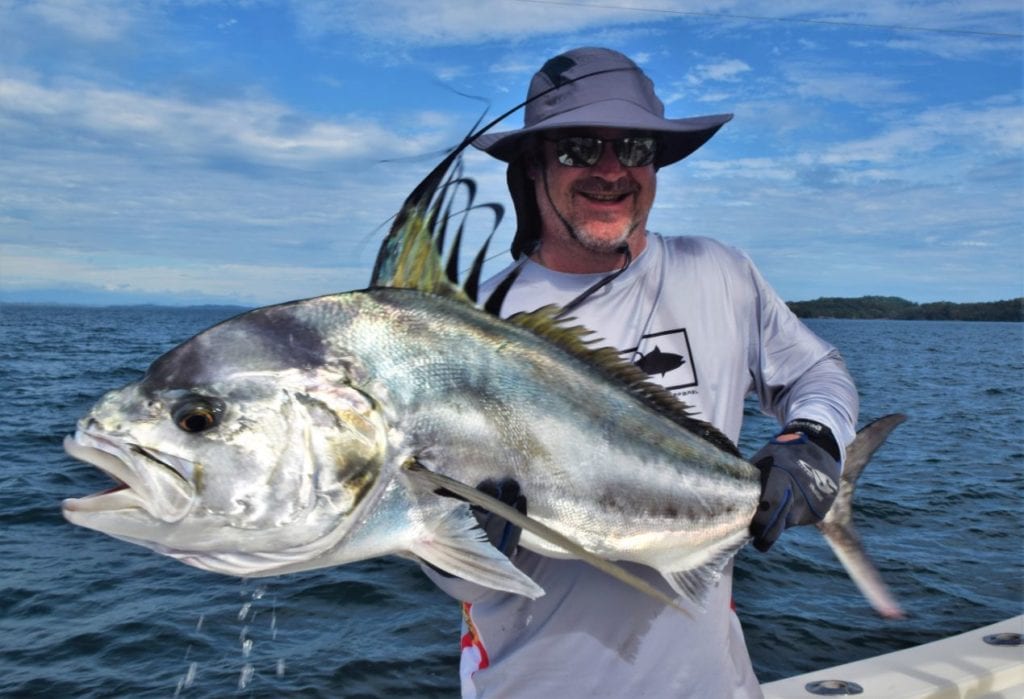 Angler holding roosterfish with Isla Parida in the background