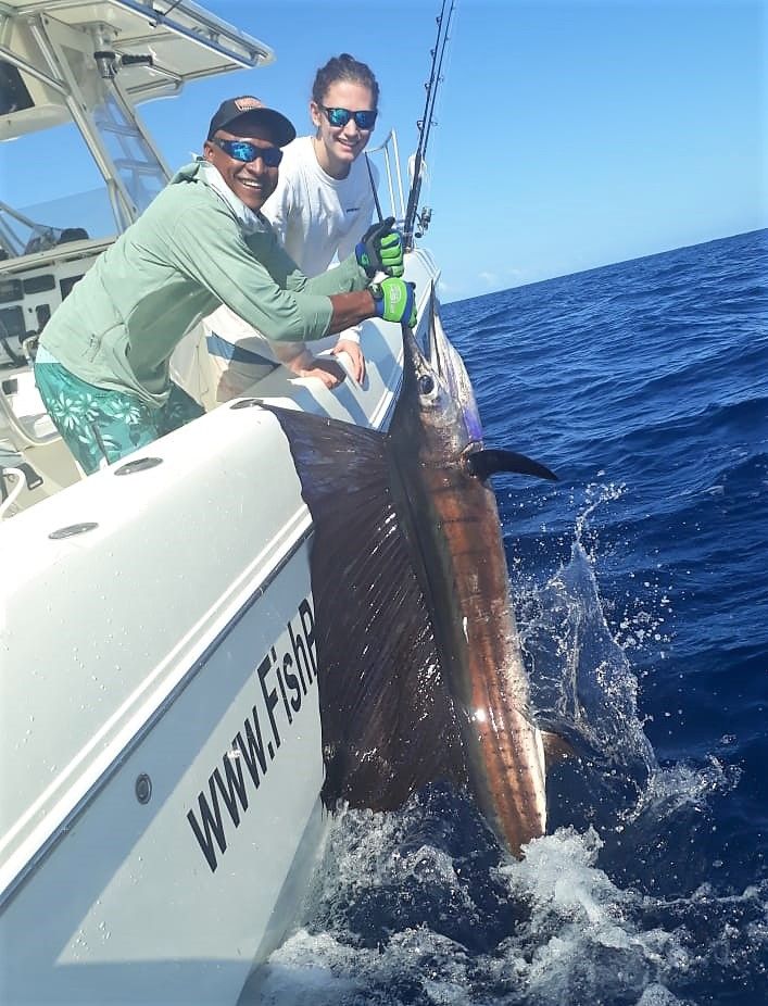 Smiling mate holding sailfish for release for lady angler