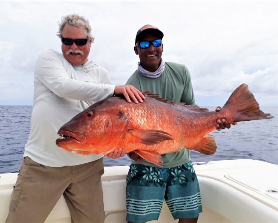 Mate holding cubera snapper for picture with angler