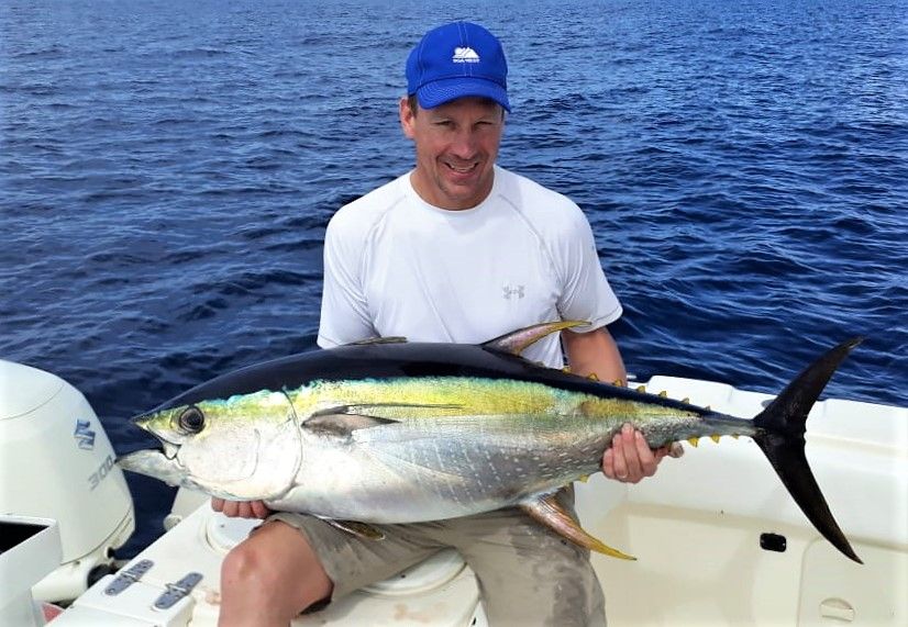 Angler with blue hat posing with small yellowfin tuna