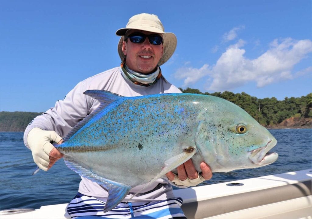 man holding blue travelly fish