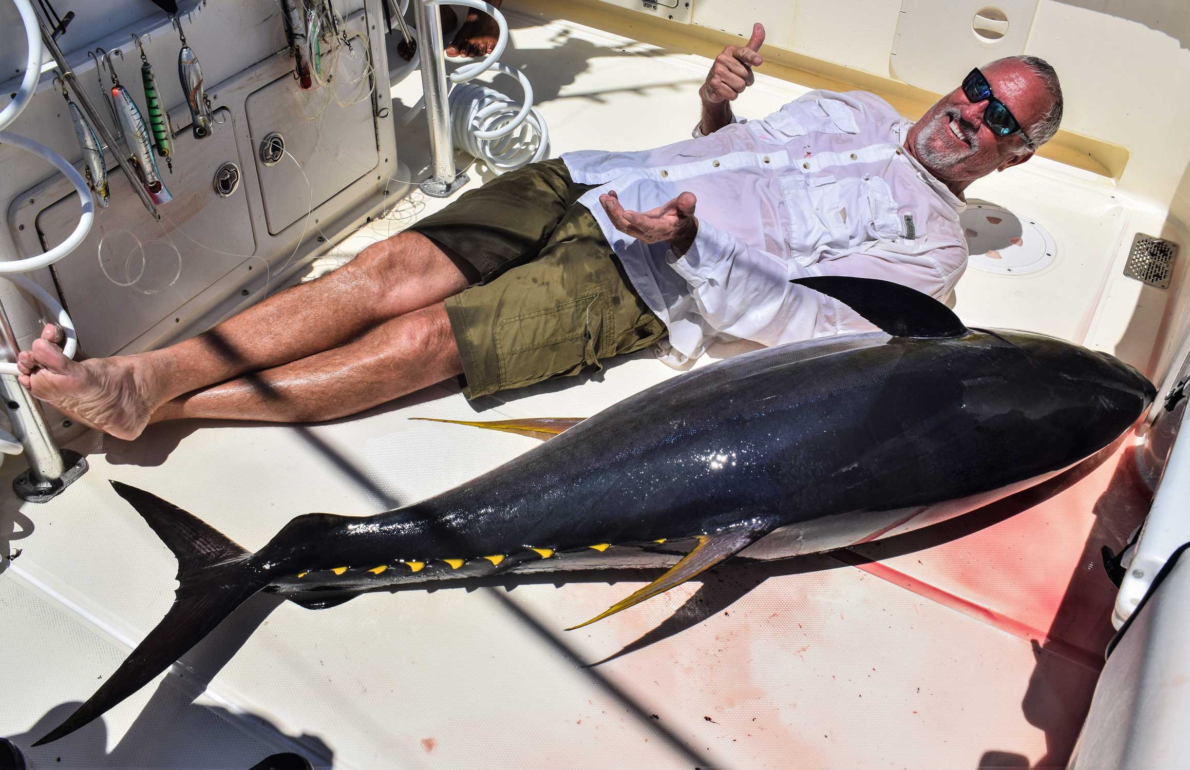 Angler laying on deck with large tuna