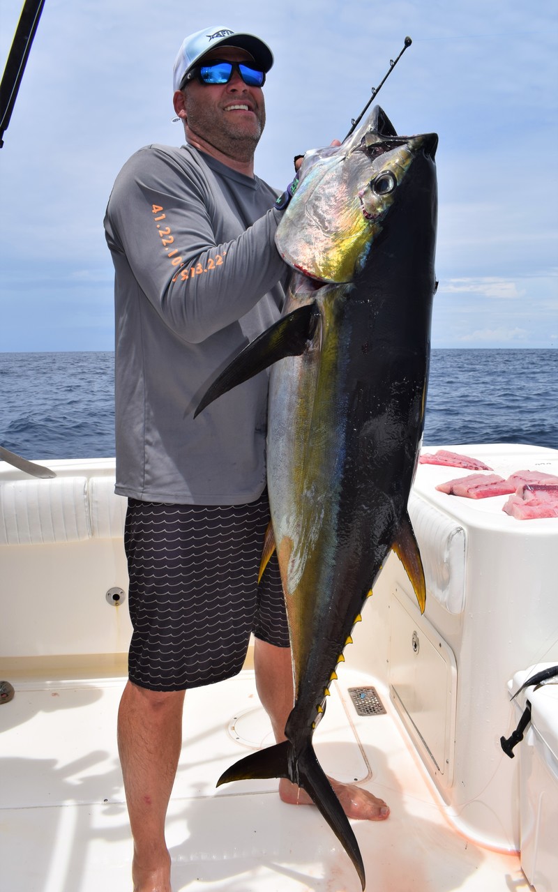 Angler straining as he holds yellowfin tuna