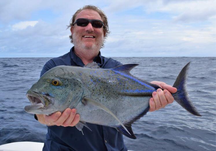 Angler posing with Bluefin Trevally